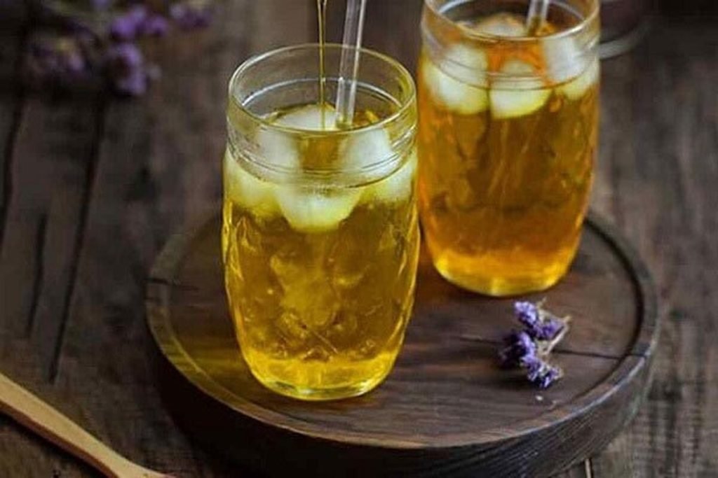 Glass of pale golden cold saffron water served as a simple summer drink