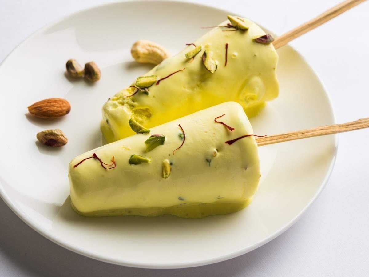 Kesar Kulfi Rezept – indisches Safran-Eis mit Pistazien, Mandeln und goldgelber Farbe, serviert auf einem Teller mit Eiswürfeln
