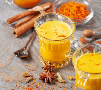 oldene Milch mit Safran und Honig in einem Glasbecher – cremiges, gesundes Getränk für innere Wärme.