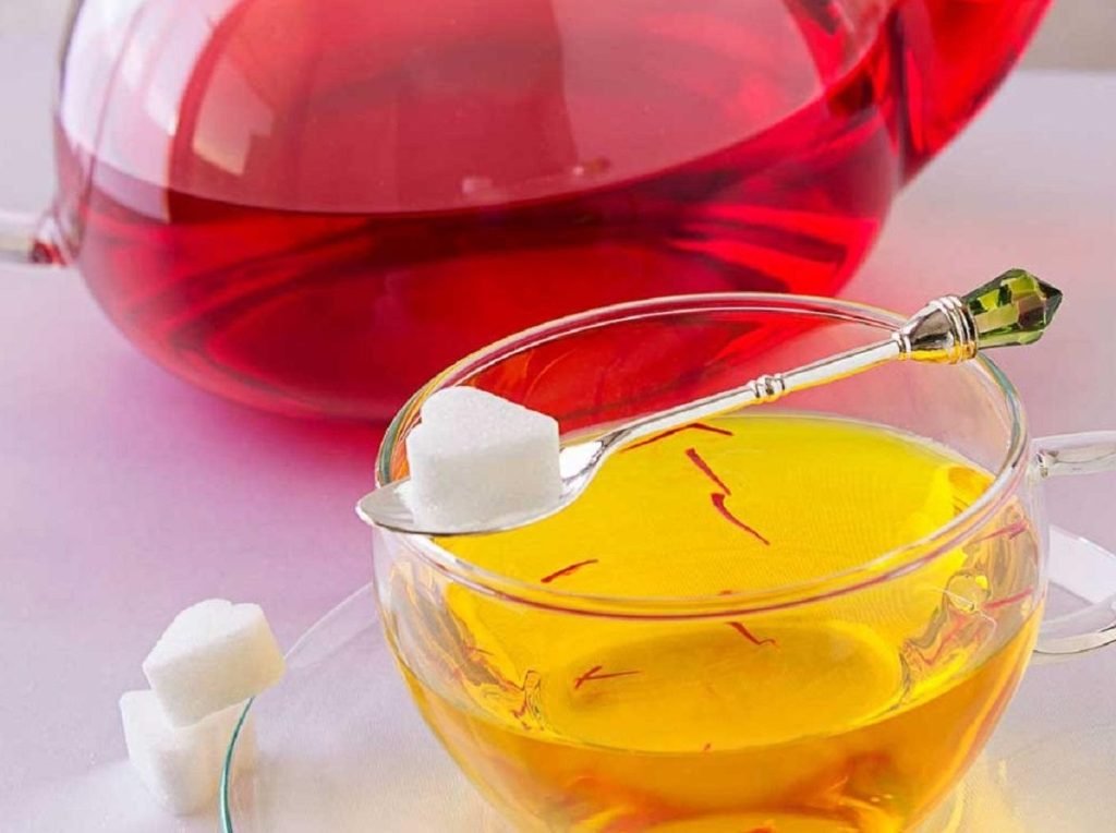 Safran Wasser in einer Glas- oder Keramiktasse mit hellgoldener Farbe, zubereitet aus wenigen Safranfäden als schlichtes Abendritual.