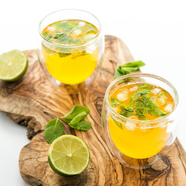 Safran Zitronenwasser in einem Glas mit hellgoldener Farbe, mit Zitronenscheibe und Eiswürfeln als erfrischendes Sommergetränk.