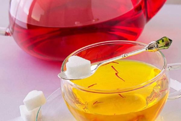 Safran Wasser in einer Glas- oder Keramiktasse mit hellgoldener Farbe, zubereitet aus wenigen Safranfäden als schlichtes Abendritual.